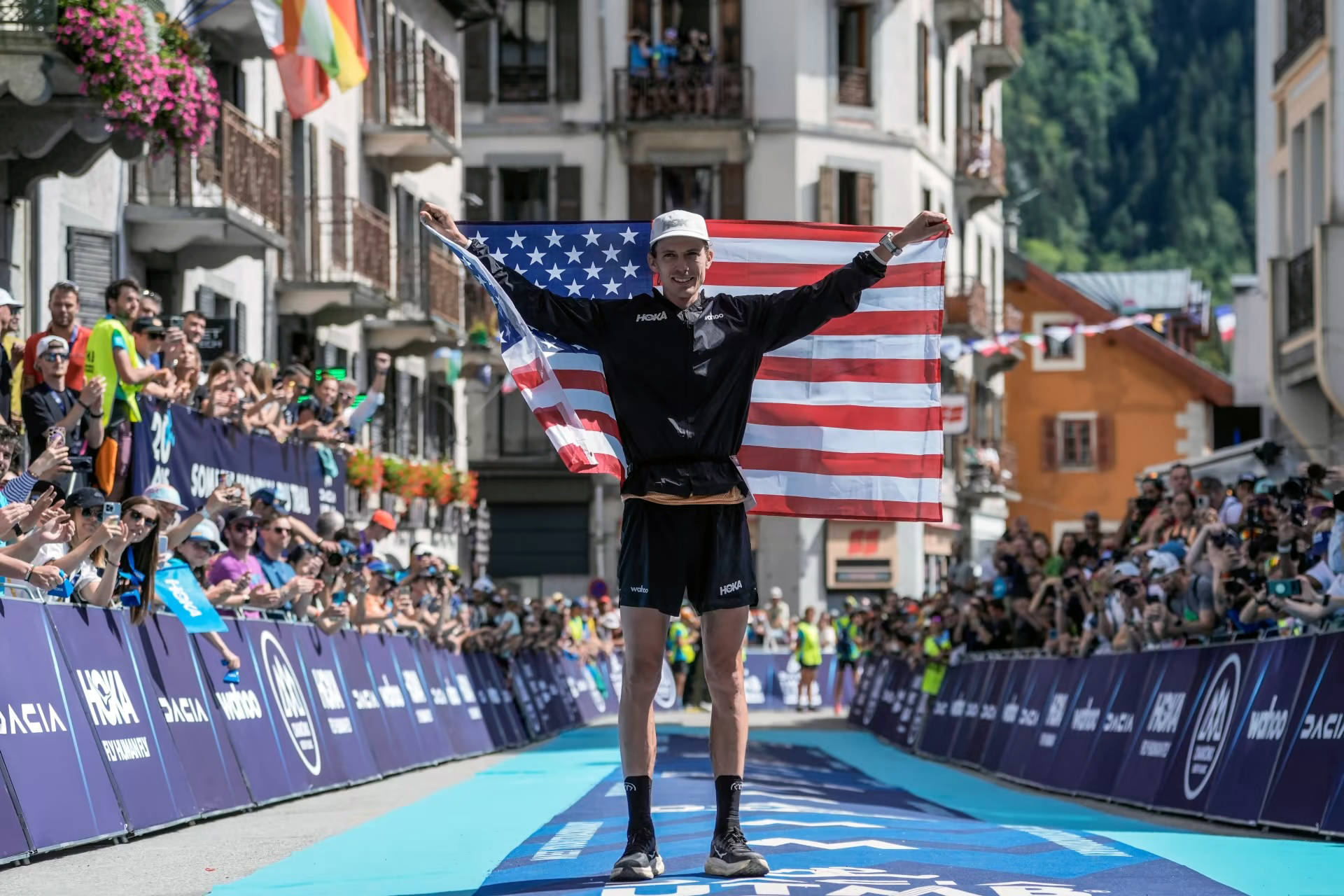 Jim Walmsley festeggia la vittoria alla UTMB con la bandiera statunitense, accolto dal pubblico di Chamonix.