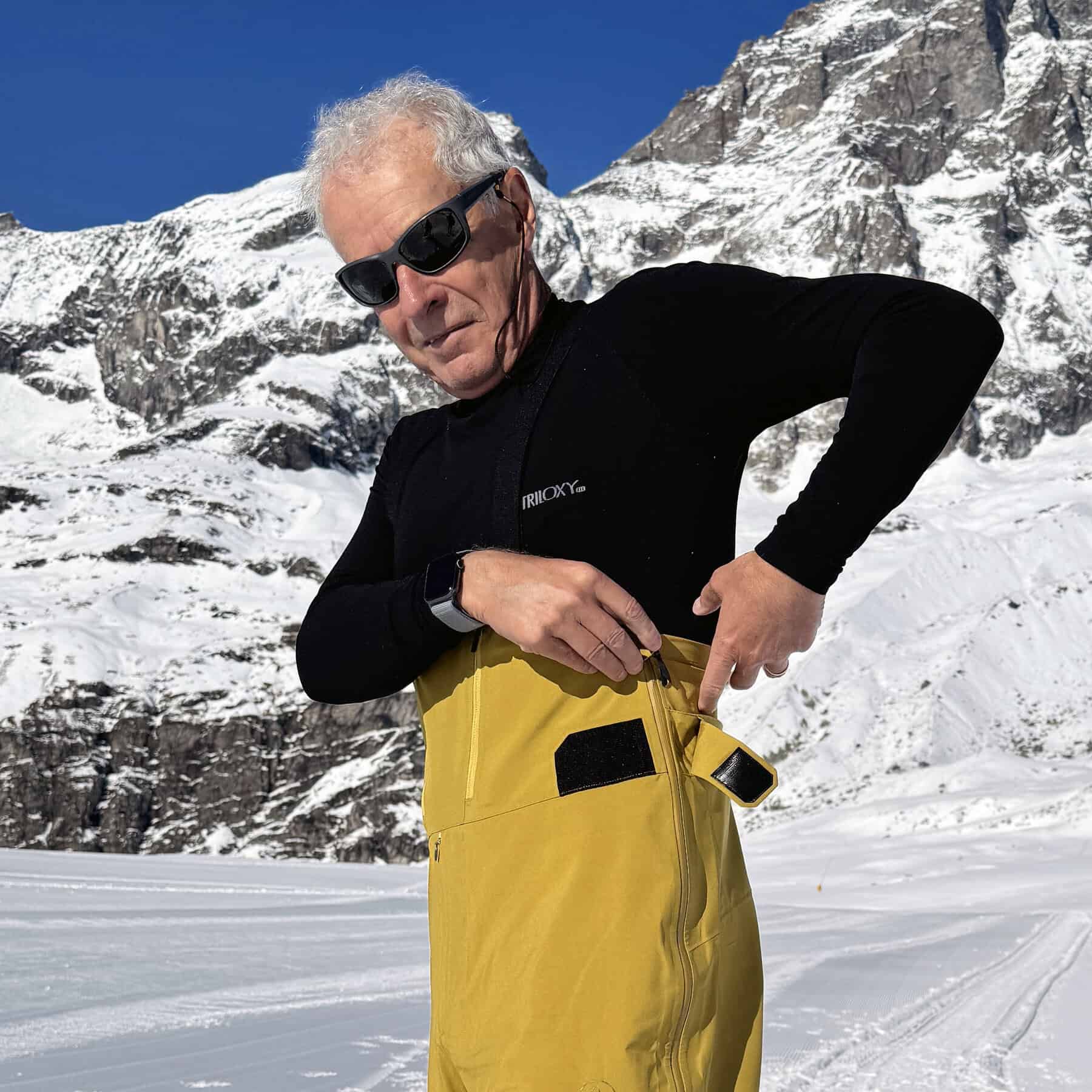 Compressore portatile per attività all'aperto in inverno, con uomo in abbigliamento da neve e montagne innevate sullo sfondo.