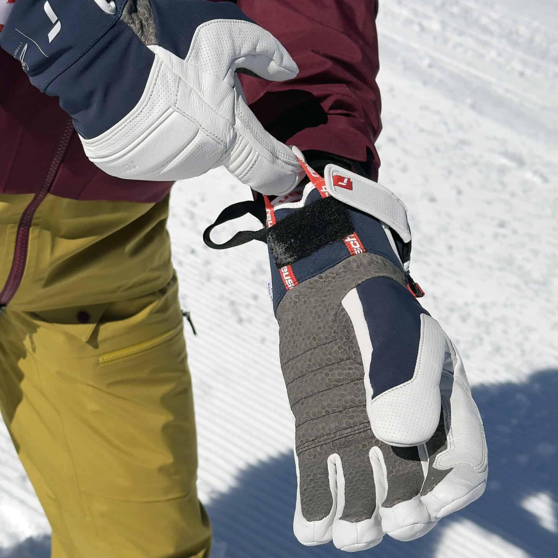 Dettaglio di guanto da sci alpino con chiusura regolabile in velcro e anello di trazione per indossaggio facilitato.