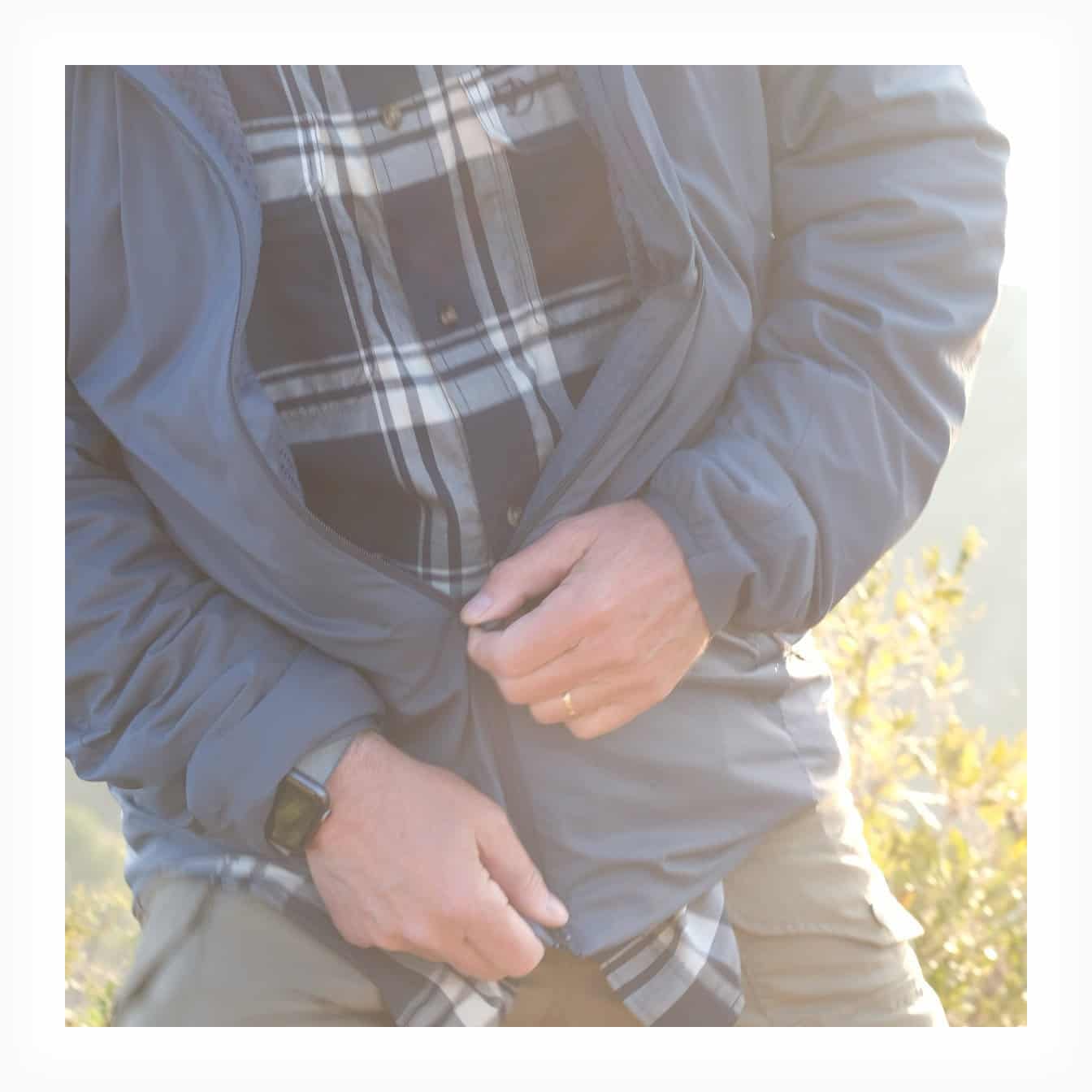 Layering trekking: giacca a vento aperta con camicia a quadri in flanella visibile sotto, outfit trekking Finale Ligure