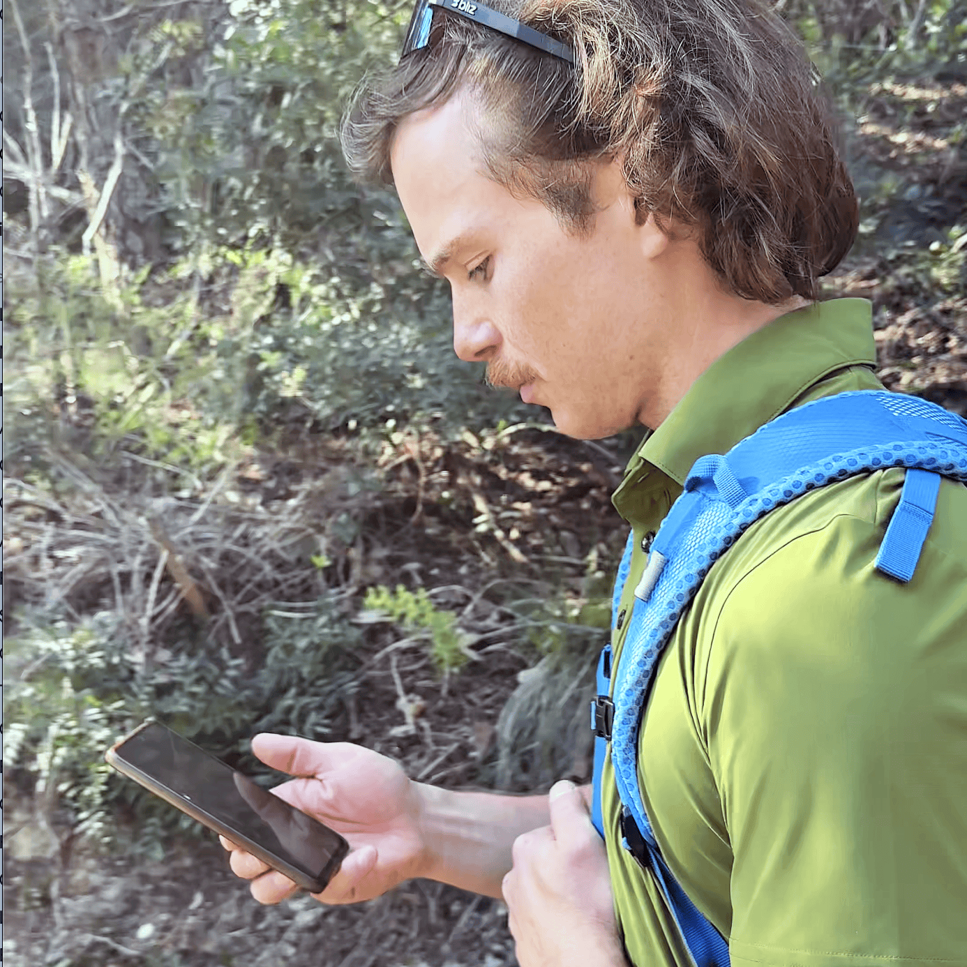 Tester Outdoortest consulta la app PeakVisor sullo smartphone durante un'uscita di test nel Finalese