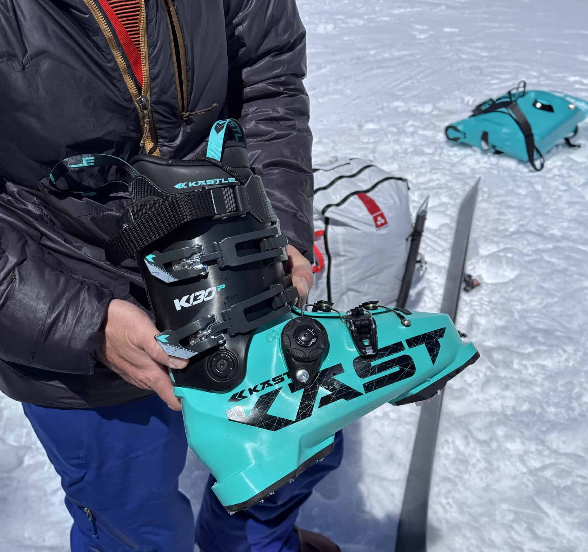 Scarpone da sci Kästle K130 colore turchese e nero con leva RYF tenuto in mano sulla neve