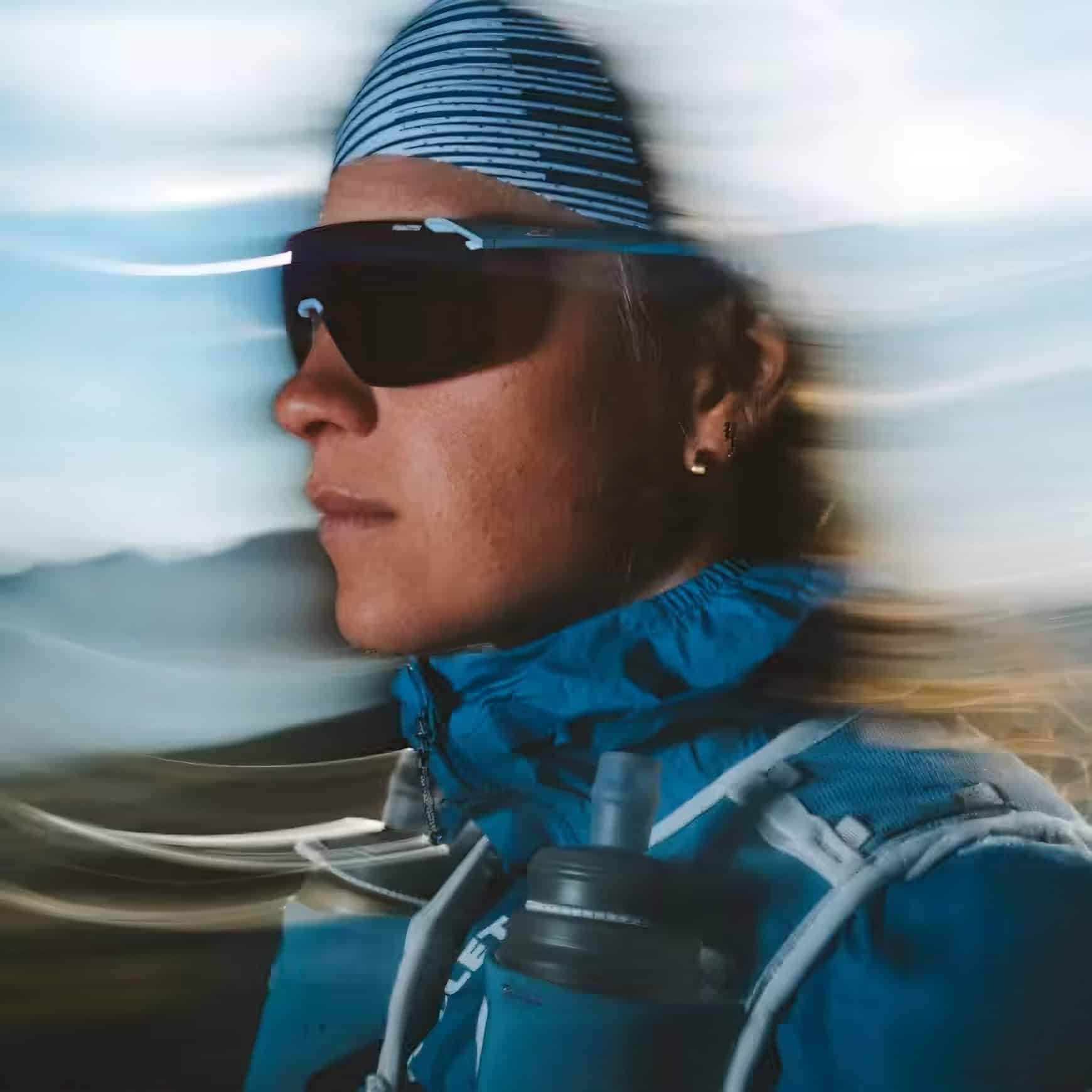 Donna indossa occhiali da sole Julbo e berretto a righe in ambiente montano